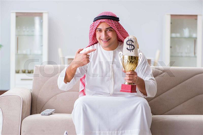 Arab man with prize and money on sofa, stock photo