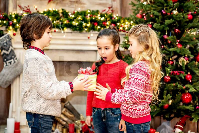 Kid giving a gift box to his friends at Christmas , stock photo
