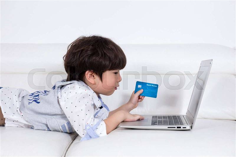 Asian Chinese little boy using laptop buying online with credit card in the living room at home, stock photo