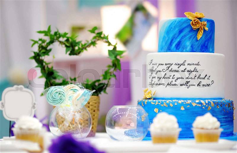 Elegant sweet table set with blue cake and cupcakes on wedding or event party, stock photo