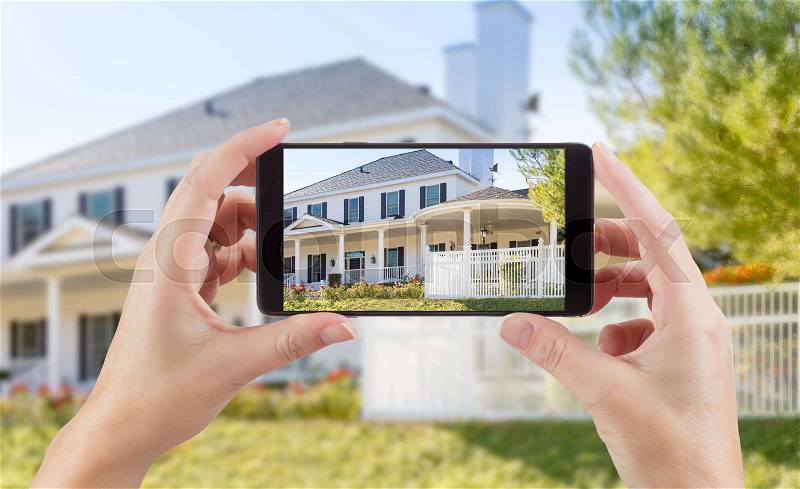 Female Hands Holding Smart Phone Displaying Photo of House Behind, stock photo