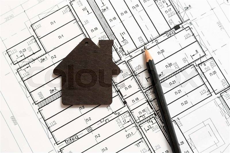 Small black toy house and black pencil on top of architecture blueprint plan, stock photo