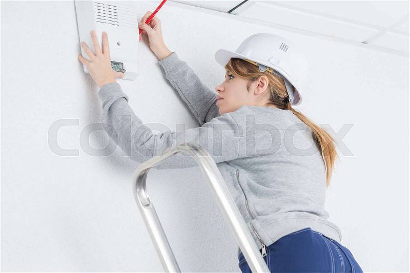 Woman fitting electrical appliance to wall, stock photo