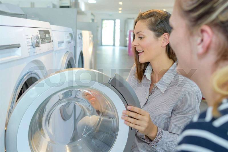 Women viewing washing machines in store, stock photo