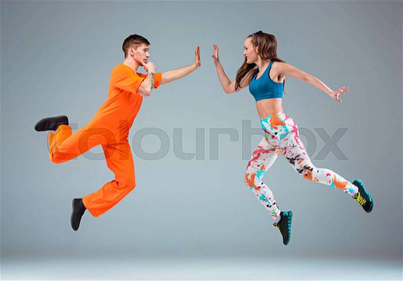 The man, woman jumping and dancing hip hop choreography and posing at studio on gray, stock photo