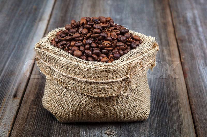Coffee beans in a canvas bag on a wooden background, stock photo