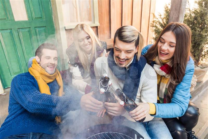 High angle view of cheerful friends sitting on porch with beer on barbeque, stock photo