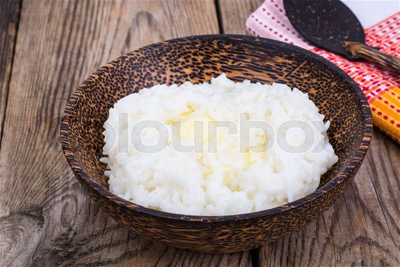 Milk rice porridge with butter in wooden bowl. Studio Photo, stock photo