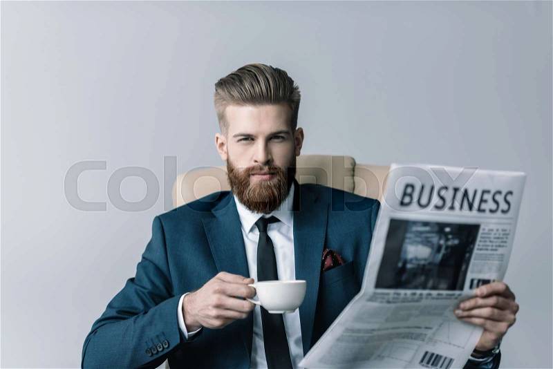 Portrait of confident businessman holding cup of coffee and newspaper, stock photo