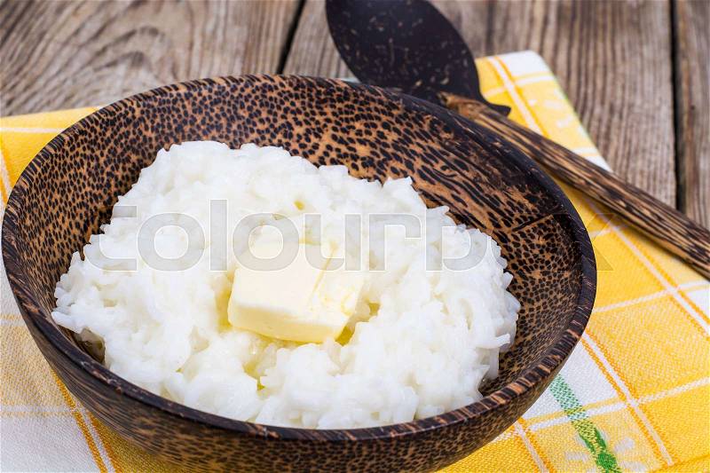Milk rice porridge with butter in wooden bowl. Studio Photo, stock photo