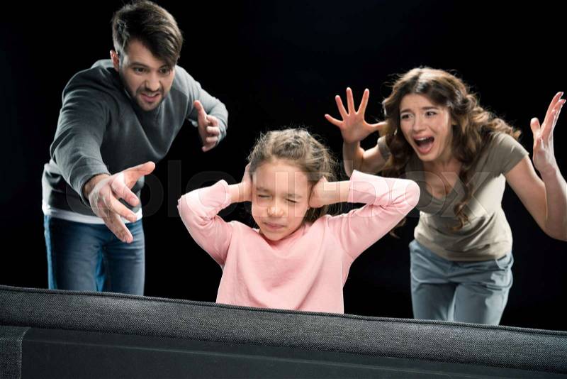 Emotional parents screaming at little daughter closing ears with hands, family problems concept , stock photo