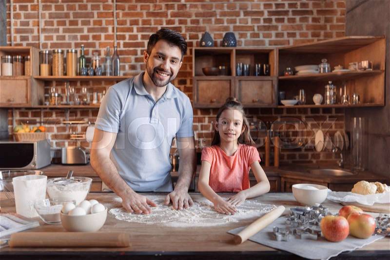 \'Happy father and daughter cooking together and smiling at camera, stock photo