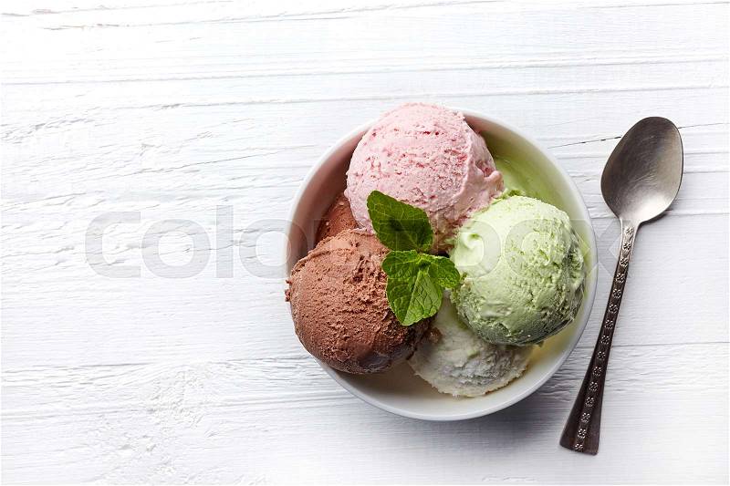 Bowl of various colorful ice cream balls on white wooden background. From top view, stock photo