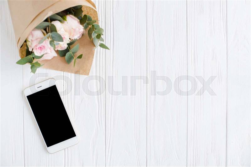 Simple feminine background with smartphote mock-up and roses on white wooden tabletop, elegant lady blogger workspace, stock photo
