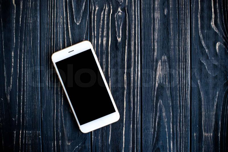 White isolated screen smartphone mock-up on black wooden table board background, stock photo