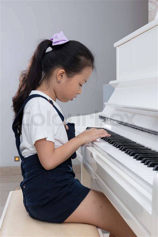 Asian Chinese little girl playing classical piano in the living room at home, stock photo