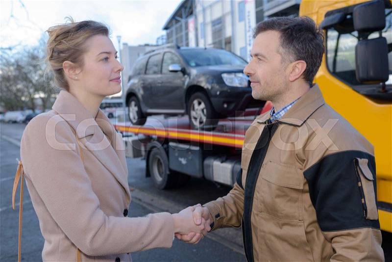 Recovery driver shaking hands with owner of car, stock photo