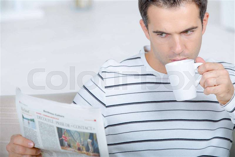 Reading the newspaper as her drinks his coffee, stock photo