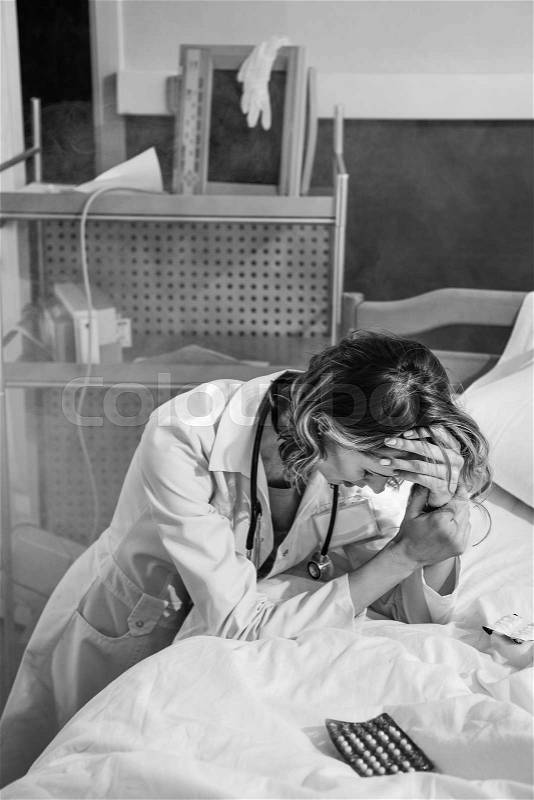 Black and white photo of upset doctor in uniform in ruined hospital chamber, stock photo