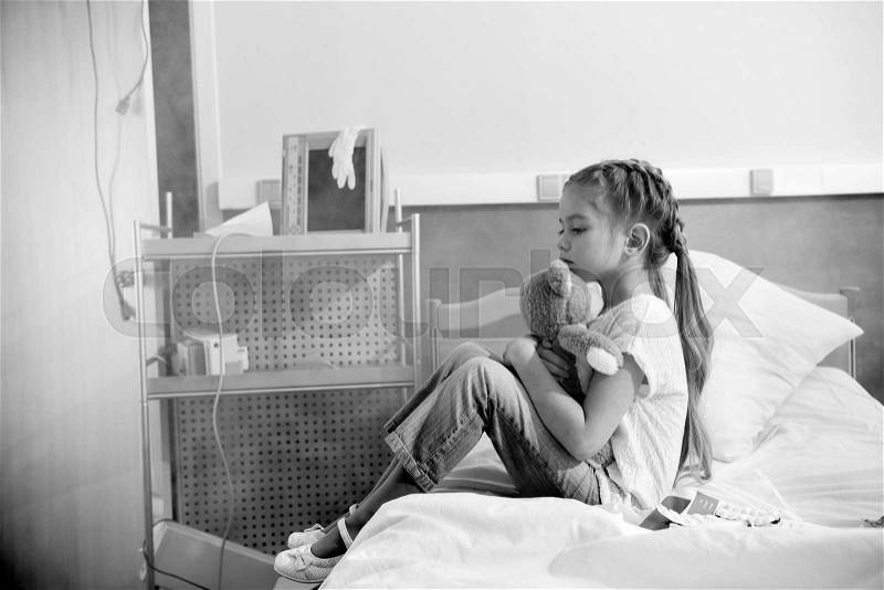 Side view of girl with teddy bear in hospital, black and white photo, stock photo