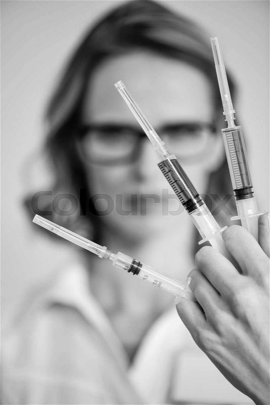 Close-up view of doctor holding syringes, black and white photo, stock photo