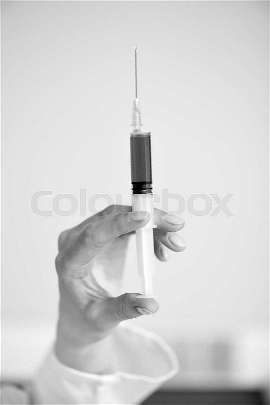 Close-up partial view of doctor holding syringe, black and white photo, stock photo