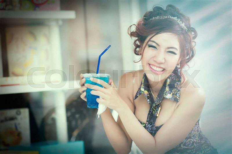 Beautiful young woman in cafe drinking blue soda ice and relaxing on a summer day, adding film grain, stock photo