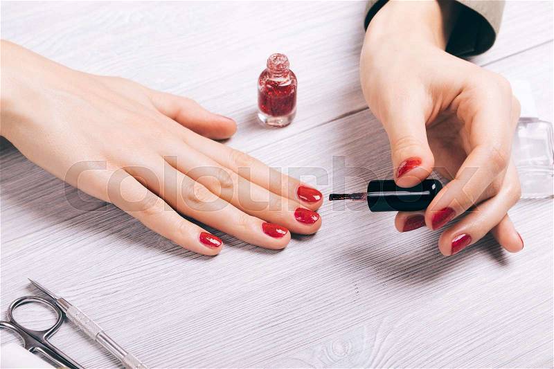 Close-up of a woman painting her nails with red lacquer, stock photo