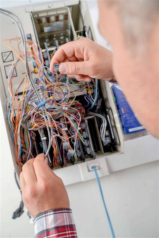 Man holding cables in electrical box, stock photo