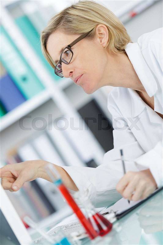 Beautiful female lab worker holding up test tube, stock photo