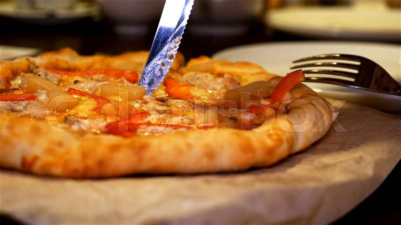 Cutting and serving Italian pizza with meat, bacon, pepperoni and cheese, stock photo