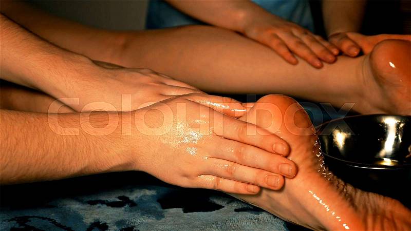 Woman gets four hands Indian oil massage on her legs and foots. Manual alternative therapy for female wellness beauty relaxation and skin, stock photo