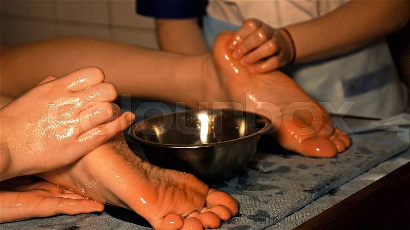 Woman gets four hands Indian oil massage on her foots and legs. Manual alternative therapy for female wellness beauty relaxation and skin, stock photo