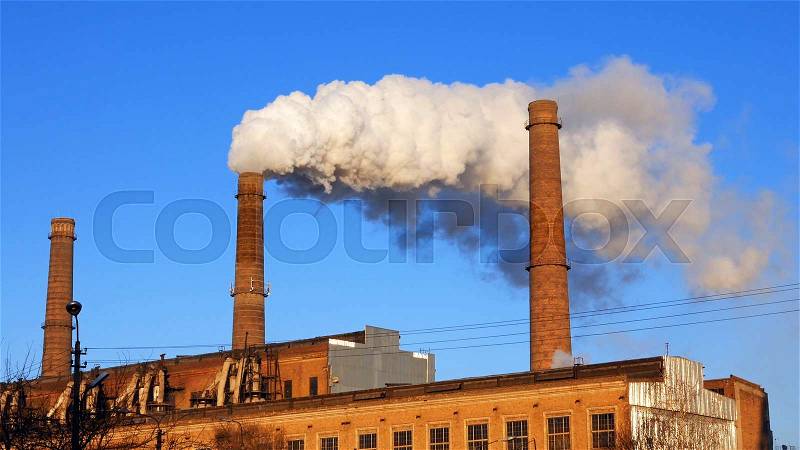 Factory plant puffs smoke stack over blue sky background. Energy generation and air environment pollution industrial scene, stock photo