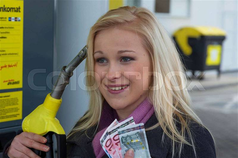 A young woman tank gasoline on a gas station. the cost of the car are due to gasoline prices more expensive, stock photo