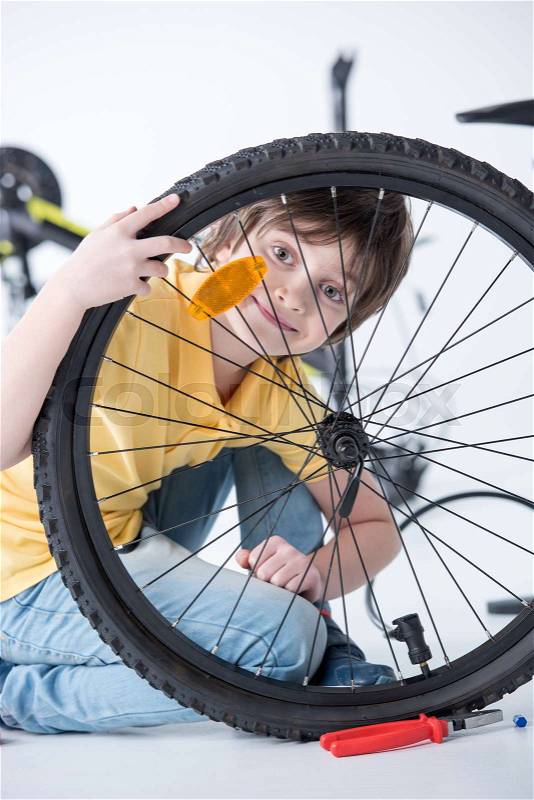 Little boy repairing bicycle tire in studio on white, stock photo