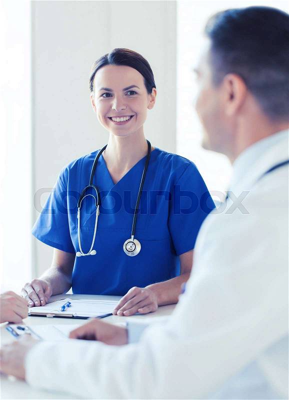 Health care, profession, people and medicine concept - group of happy doctor and nurse with stethoscope and clipboard meeting and talking at hospital, stock photo