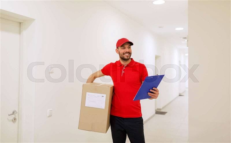 Delivery, mail, people and shipment concept - happy man in red uniform with parcel box and clipboard in corridor, stock photo