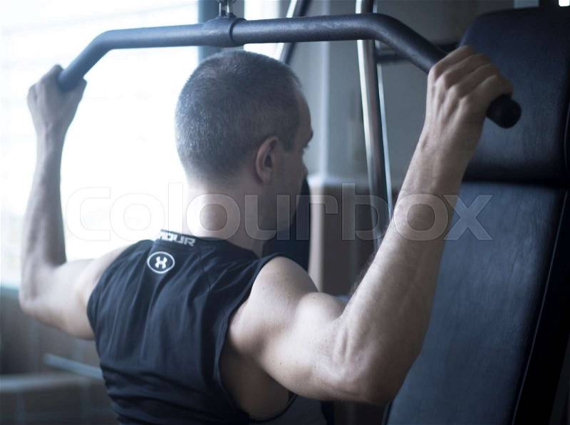 Man in 40\'s gym weight training with dumbells to gain muscle mass and get fit in exercise program training, stock photo