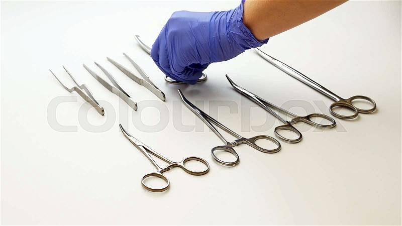 Surgical nurse in protective gloves prepares and puts medical surgery tools on table, stock photo