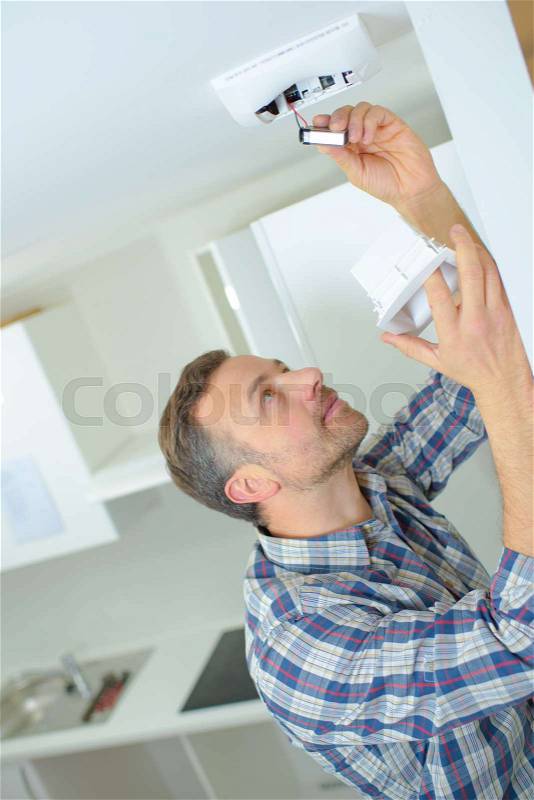Safety conscious man fitting a fire smoke alarm, stock photo
