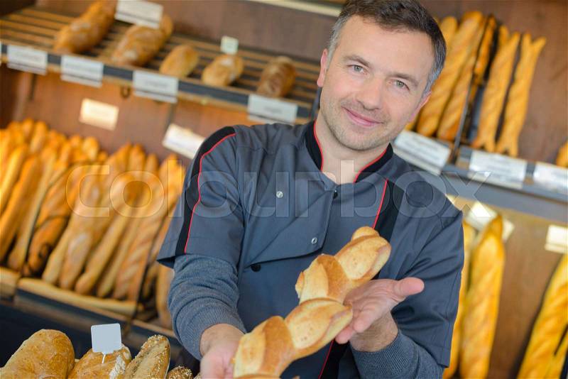 Baker showing baguette, stock photo