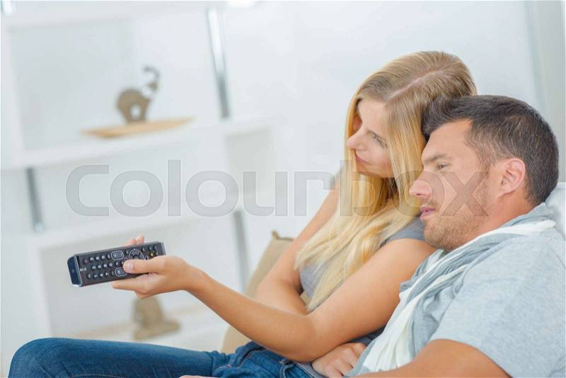 Playful couple fighting over the TV remote, stock photo