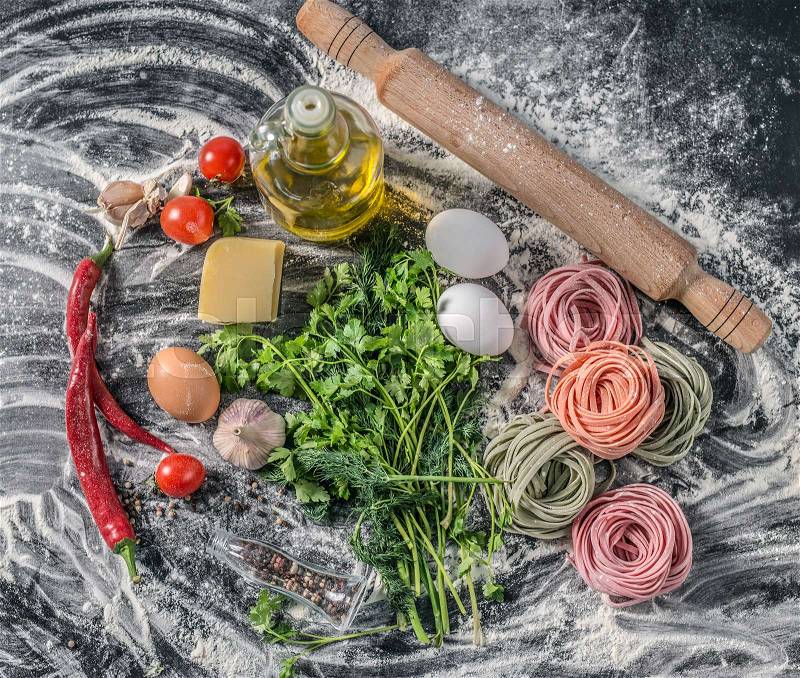 Rustic looking bottle of oil, pepper and herbs, pasta and scattered flour, stock photo