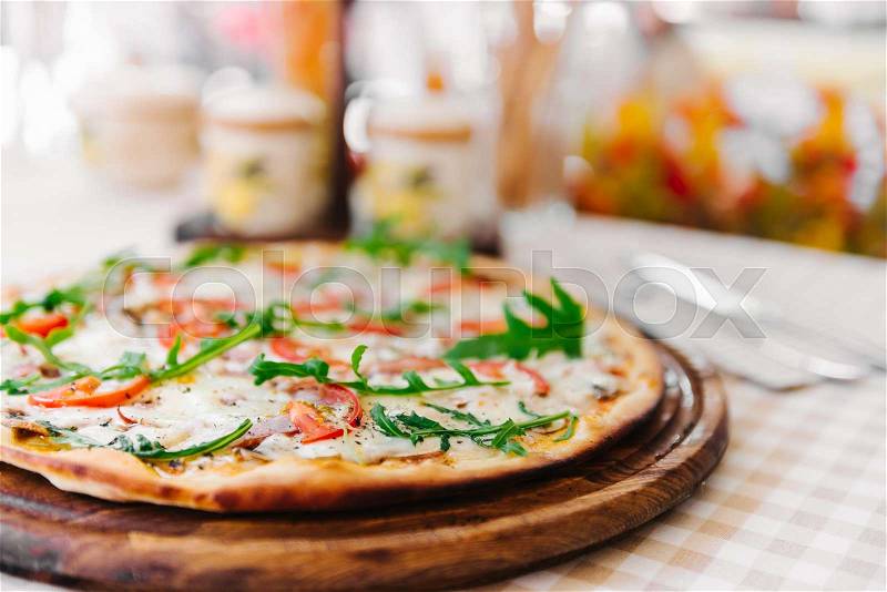 Pizza with cheese, tomato and meat, on served table with plaid tablecloth, stock photo
