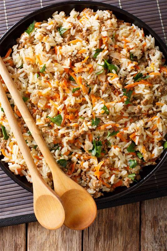 Fried spicy rice with minced meat and vegetables close-up on the table. Vertical view from above , stock photo