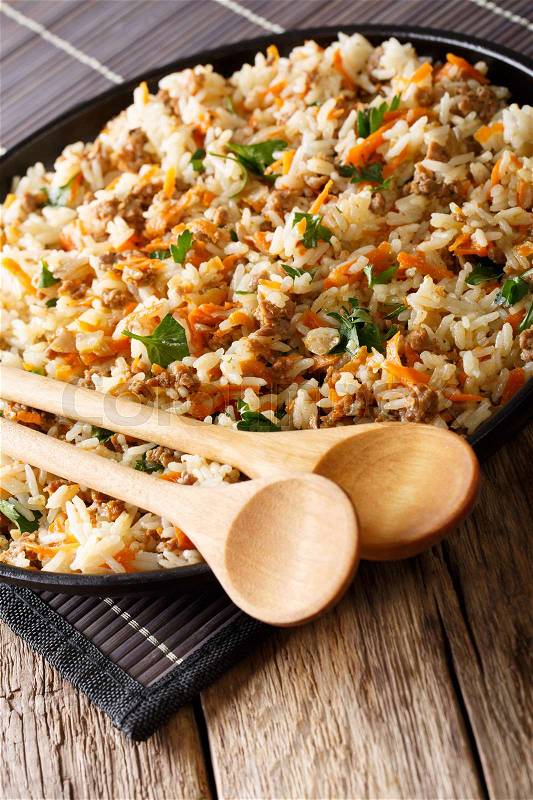Hot rice with minced meat and carrots close-up on a plate on a table. vertical , stock photo