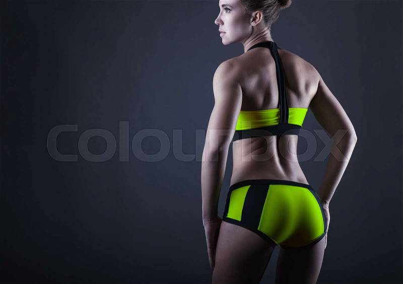 Young sports woman shows her athletic figure. Back view, stock photo