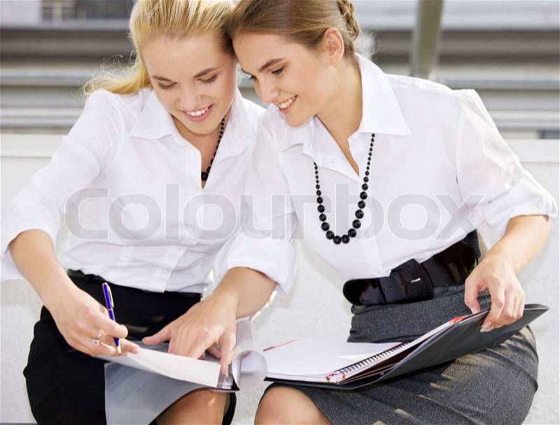 Picture of two happy businesswomen with documents, stock photo