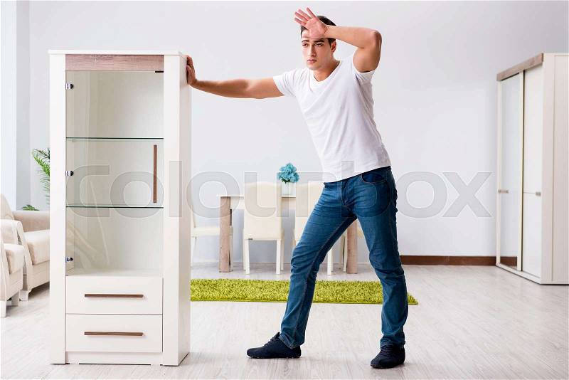 Young man moving furniture at home, stock photo